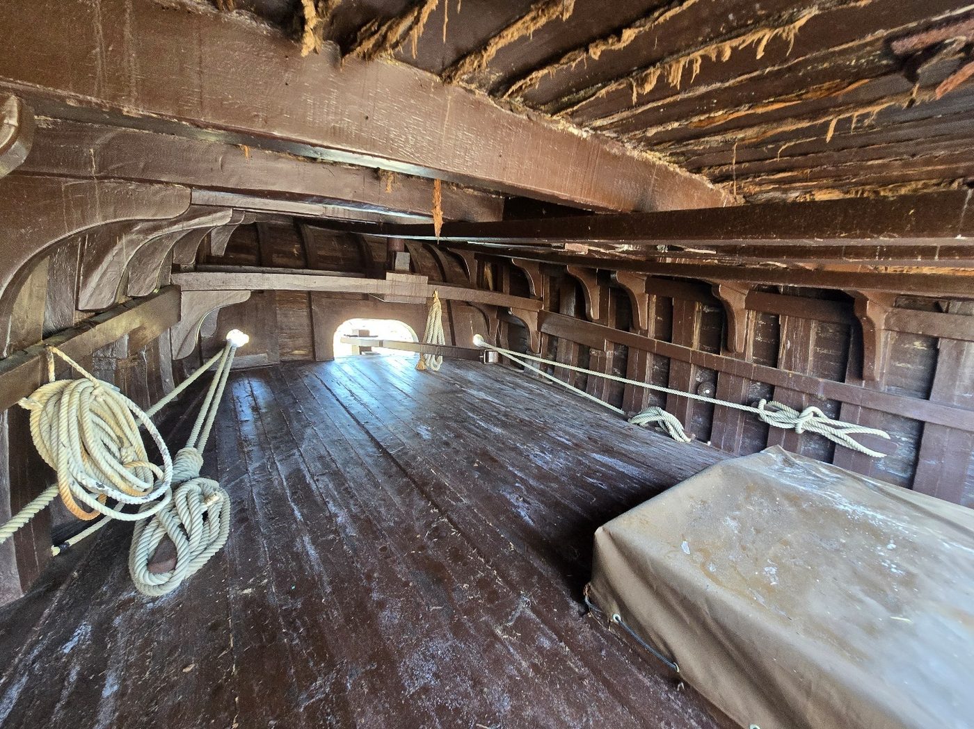 A cramped below-deck cabin space with low wooden beams